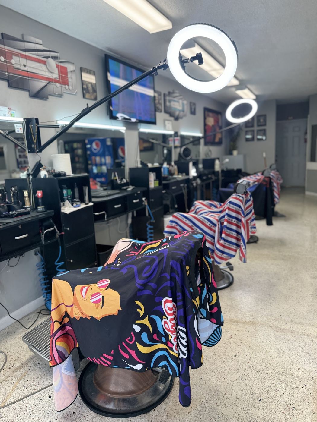Interior de la barbería con sillas y capas de colores